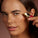 Woman applying Tropic Skincare Eye Lift Exosome Midnight Balm under her eye, with small dots of the product on her skin and the applicator’s gold tip held close to the area.